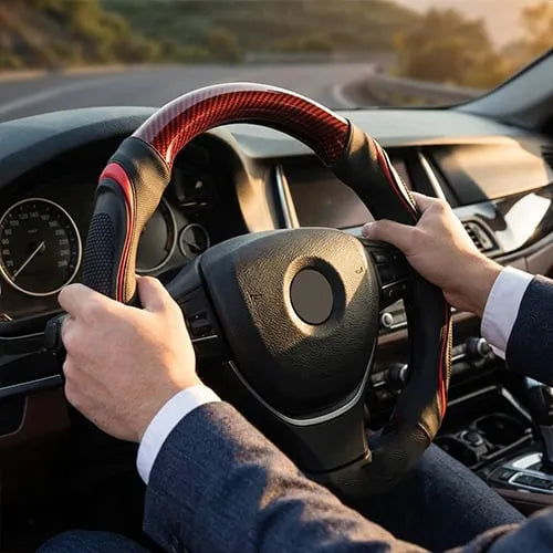 Driver holding a red sport-style steering wheel cover in a car